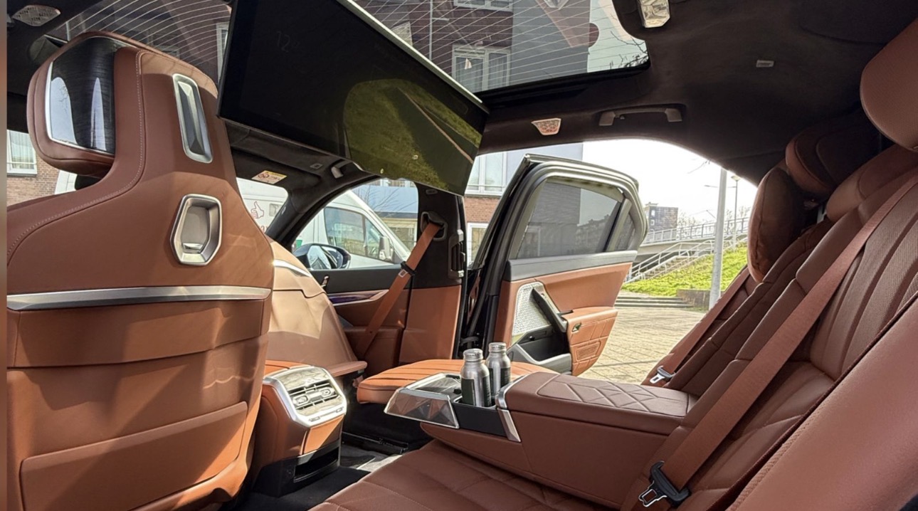 Rear cabin of the AmstelCab BMW i7 with cognac leather seats, doors open and water bottles in the centre console — the i5’s larger sibling