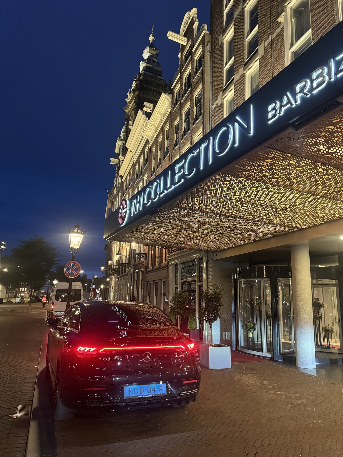 AmstelCab chauffeur car waiting at dusk outside NH Collection Amsterdam Barbizon Palace