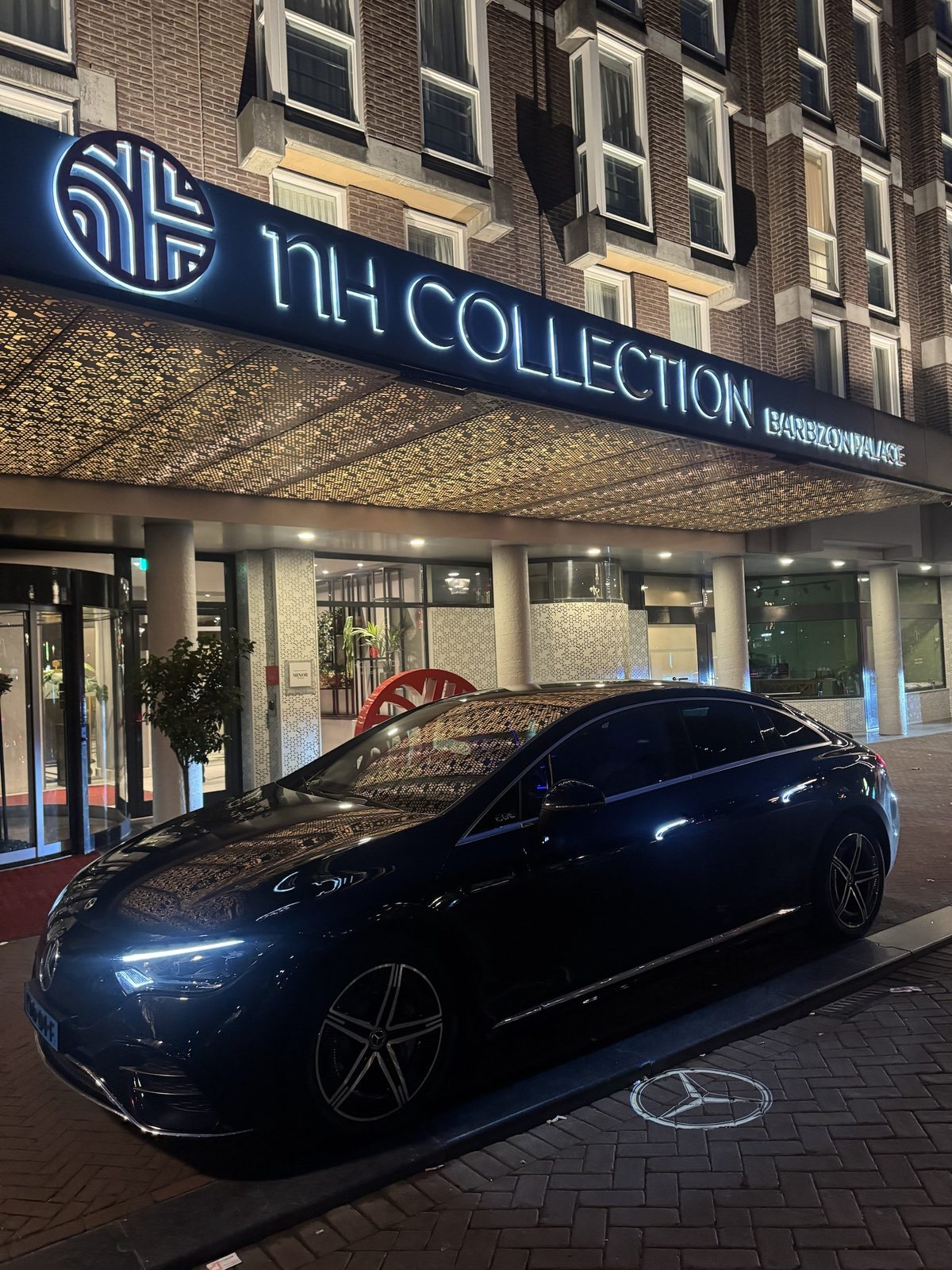 AmstelCab Mercedes-Benz EQE parked under the porte-cochere of NH Collection Amsterdam Barbizon Palace