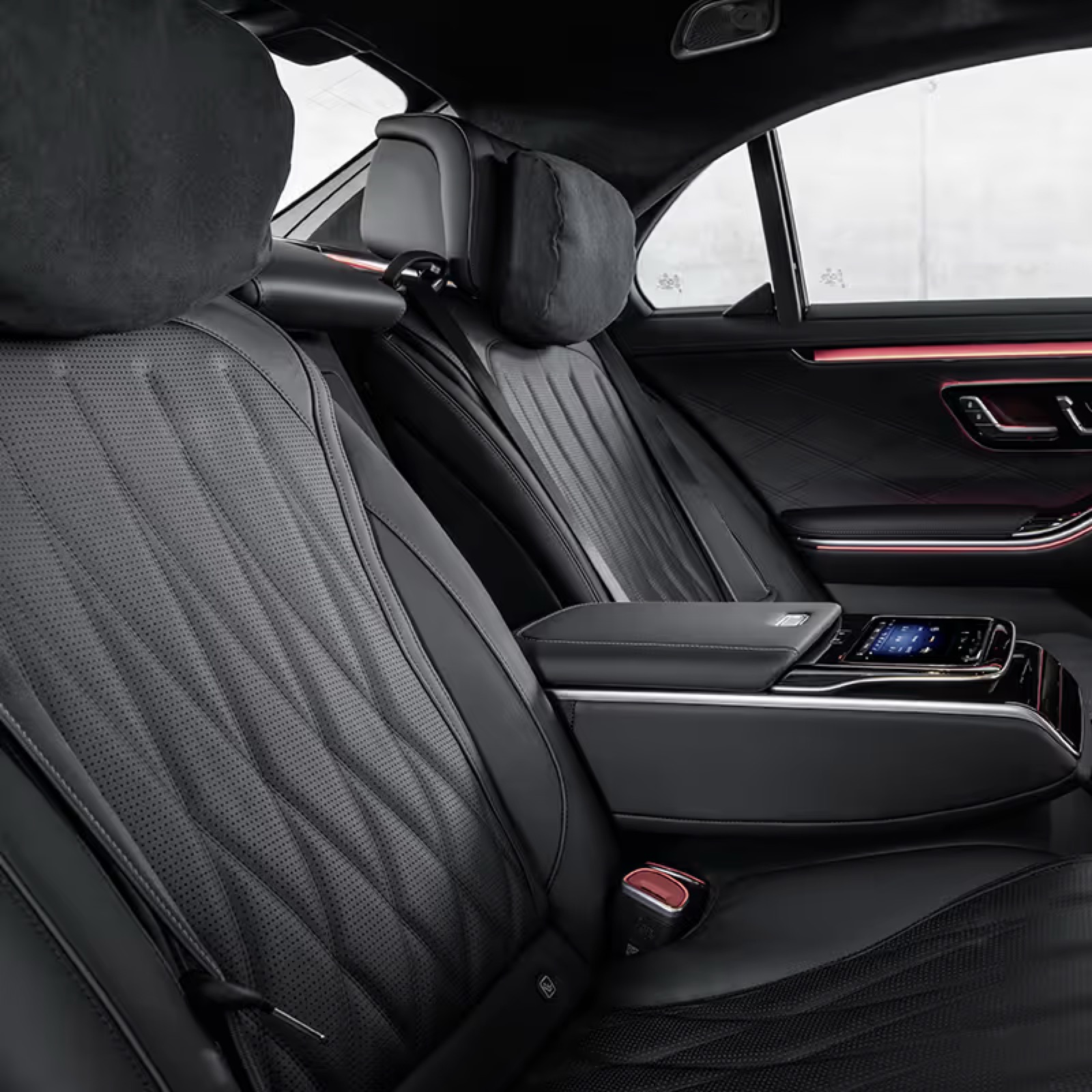 Studio photograph of the rear bench of the Mercedes flagship saloon, armrest down with its control screen and a light line along the door trim