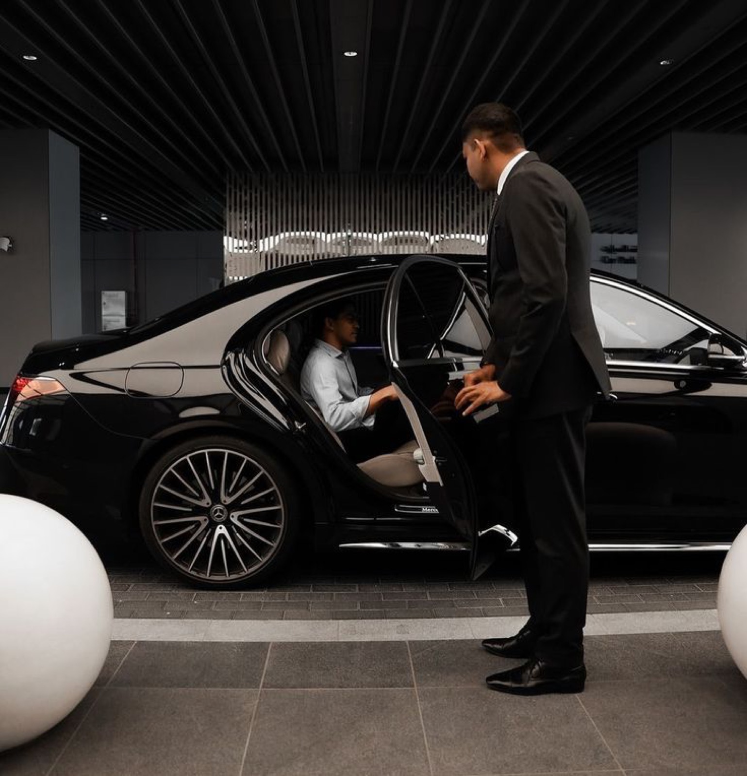 AmstelCab chauffeur holding the rear door of a Mercedes-Benz S-Class