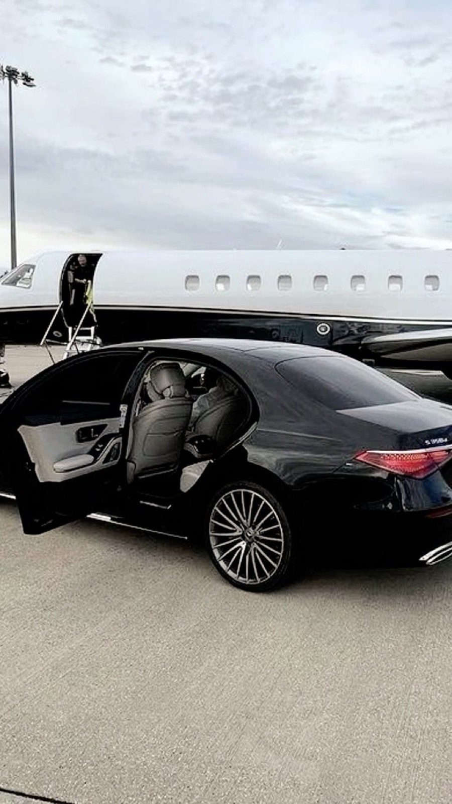 Mercedes S-Class parked beside a private jet on the apron